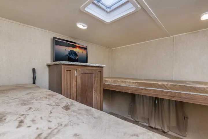 Cozy RV rental interior featuring comfortable bunk beds, a TV, and a skylight, ideal for family adventures.. Jayco Sport 2019