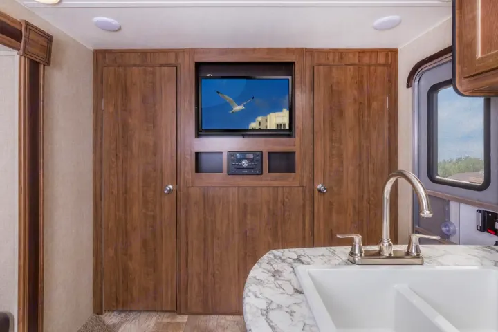 This RV rental interior features a kitchen sink, built-in entertainment system, and wood storage cabinetry, offering comfort.. Jayco Sport 2019