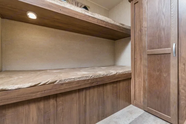 RV rental interior: two cozy bunk beds with an integrated light and adjacent storage cabinet. Ideal for compact living and sleeping.. kz connect 302 2021