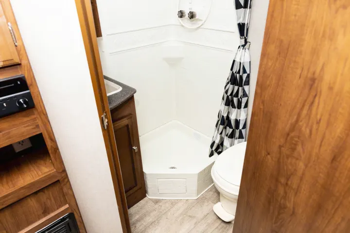 Experience comfort in this RV rental's compact bathroom, featuring a corner shower, toilet, and vanity.. Coachmen Freedom Express 2018