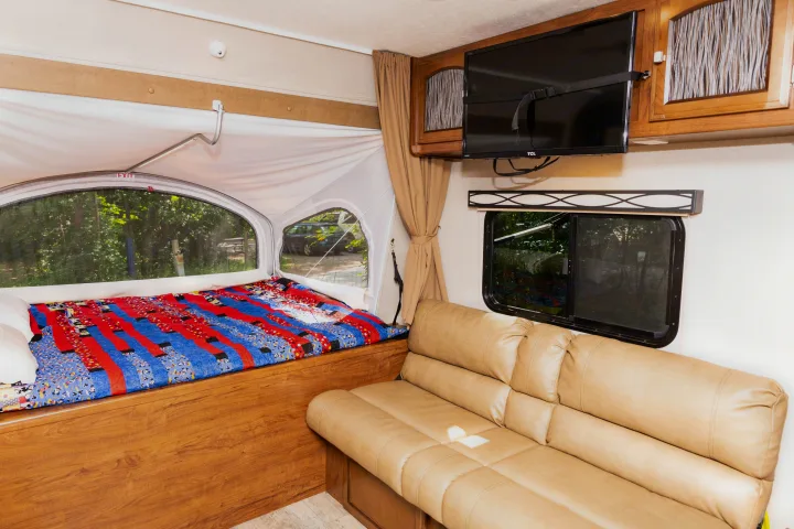 Spacious RV rental with a comfy bed, colorful blanket, TV, and sofa.. Coachmen Freedom Express 2018