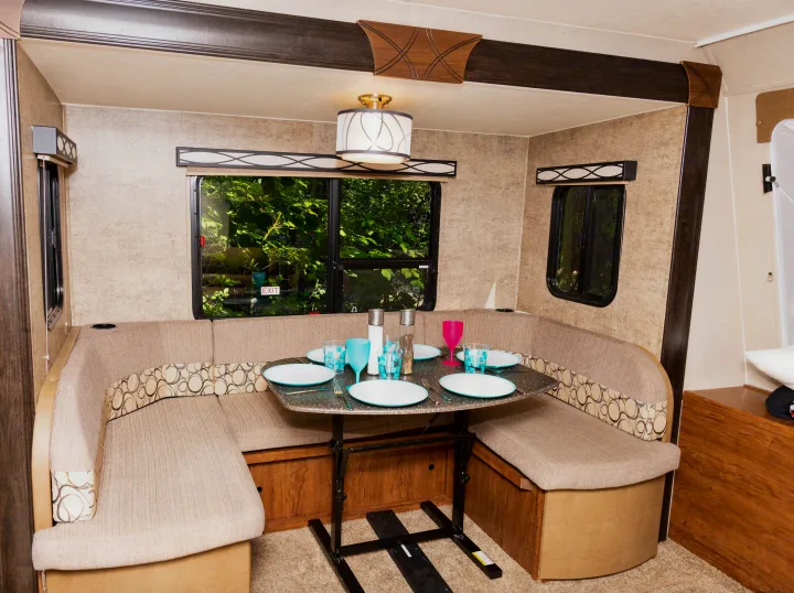 RV rental dinette interior: a cozy U-shaped booth with a set table, perfect for meals and enjoying window views.. Coachmen Freedom Express 2018