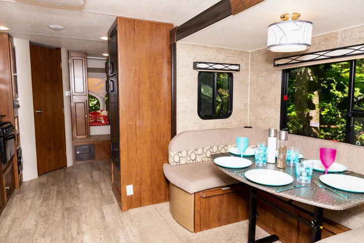 Cozy RV rental interior with dinette, kitchen, and scenic views. Table is set for a meal, ready for your adventure.. Coachmen Freedom Express 2018