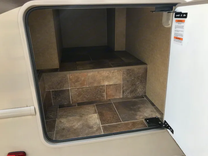 Organized storage in an RV rental, featuring multi-level, stone-look tiled flooring and textured walls, ready for your travel gear.. Thor Chateau 2020