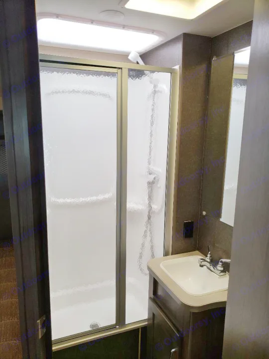 A compact, modern RV rental bathroom featuring a shower with frosted sliding doors, a white sink, and a mirror.. Winnebago Minnie Winnie 2017