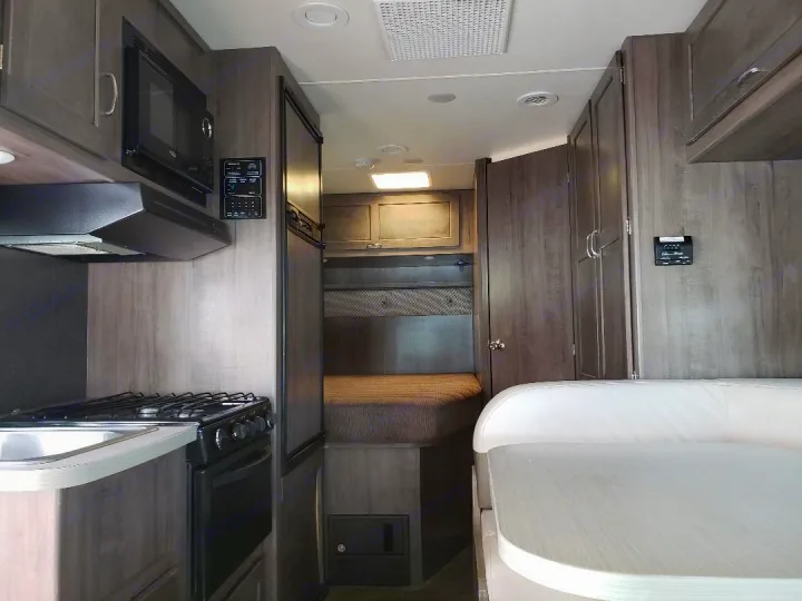 This RV rental interior showcases a functional kitchen, comfy dinette, and a sleeping area, all with modern wood finishes.. Winnebago Minnie Winnie 2017