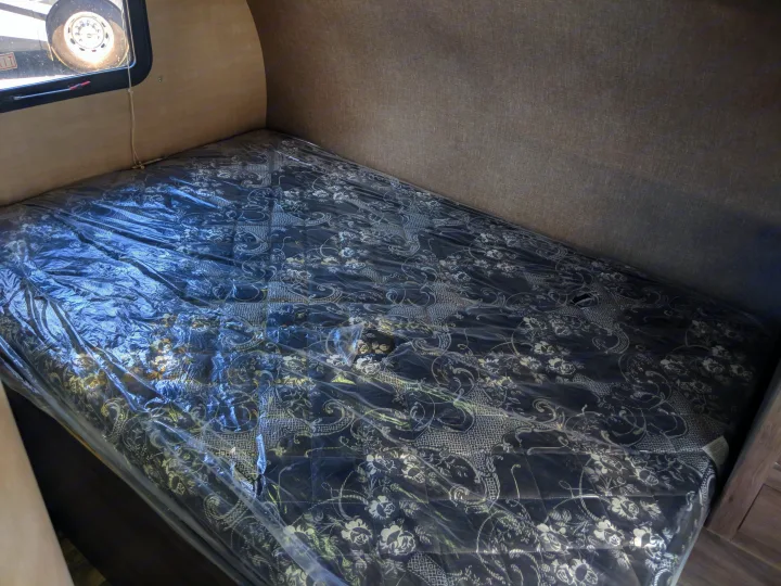 RV rental sleeping area: A new bed with a black & white patterned mattress under protective plastic.. Pacific Coachworks Blaze'N 2019