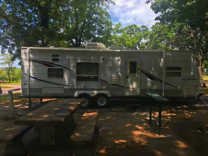 Left side profile of camper fully set up at a campground. Jayco Other 2006