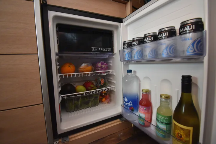 RV rental mini-fridge stocked with Maui beer, water, kombucha, wine, and fresh produce: oranges, dragon fruit, avocado.. Hymer Aktiv 2018