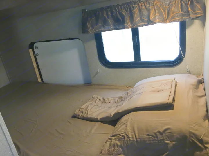 RV rental sleeping area: Cozy bed with "Happy Camper" bedding and bright window.. Keystone Hideout 2017