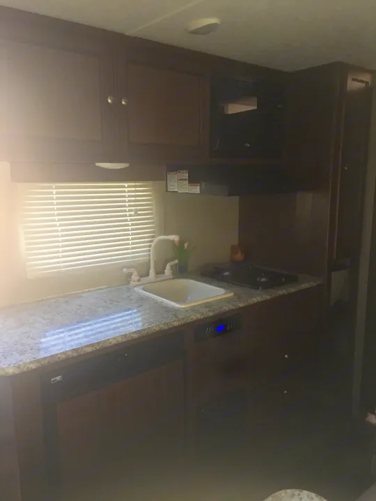 RV rental interior: practical kitchen with sink, stovetop, microwave, and fridge for comfortable travel.. Keystone Hideout 2017