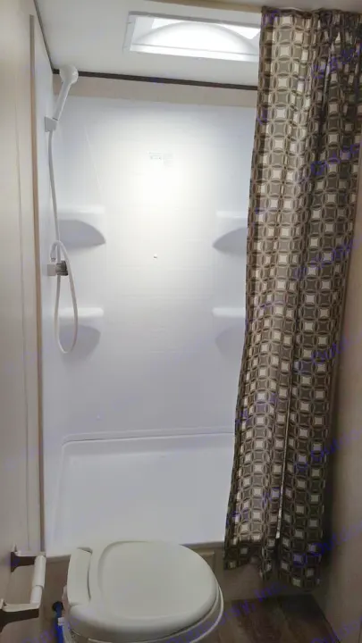 RV rental bathroom features: compact white shower stall with handheld shower, toilet, skylight, and patterned curtain.. Jayco Jay Flight 2018