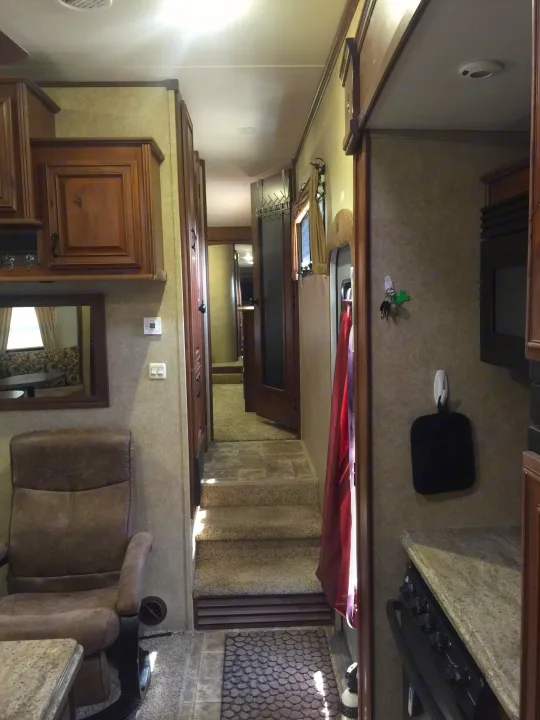 Experience comfort in this RV rental's interior: a living area, full kitchen, and hallway with steps leading to private spaces.. Open Range 427 BHS 2014