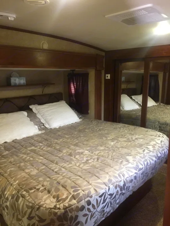 Comfortable RV rental bedroom featuring a large bed, mirrored closet, and overhead AC, perfect for travel.. Open Range 427 BHS 2014