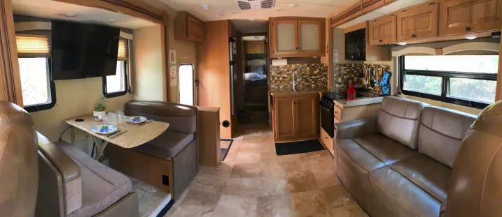 Comfortable RV rental interior featuring a dinette with TV, full kitchen, and sofa for your travels.. Thor Windsport 2018