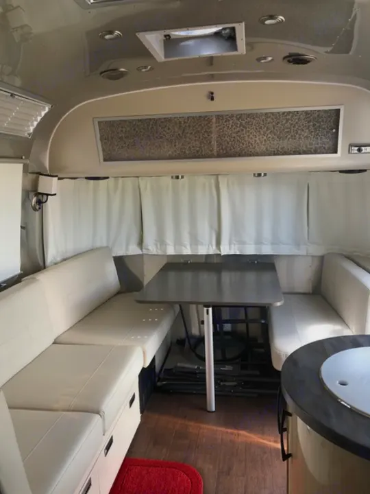 Explore this RV rental's sleek interior: comfy beige seating, dining area, and wood-look floor. Perfect for travel!. Airstream Flying Cloud 2017