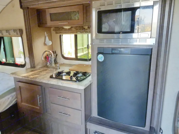 RV rental kitchen features a compact sink, two-burner stove, microwave, and Dometic refrigerator, ideal for travel.. Forest River R-Pod 2016