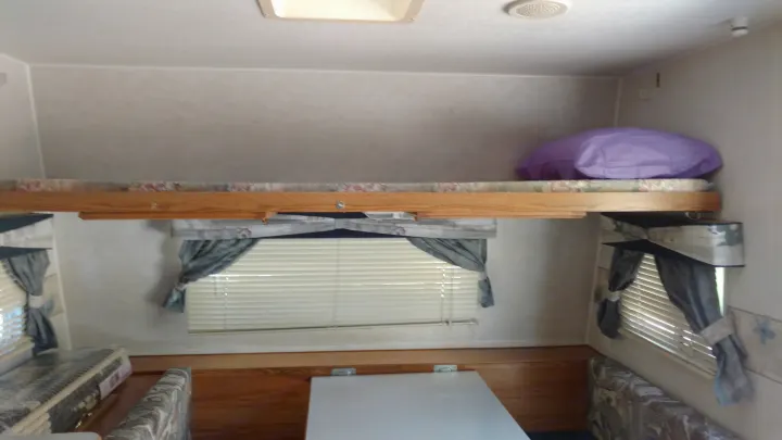 Cozy RV rental interior features a bunk bed, seating, and windows with blinds. Ready for your next adventure.. Fleetwood Prowler 2002