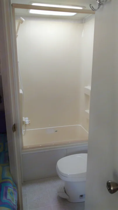 Inside an RV rental: a clean, compact bathroom with a beige shower/tub combo and white toilet on tile flooring.. Fleetwood Prowler 2002