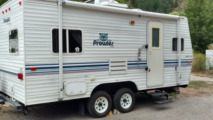 Prowler RV rental, a white travel trailer with striped detailing, parked for a trip.. Fleetwood Prowler 2002
