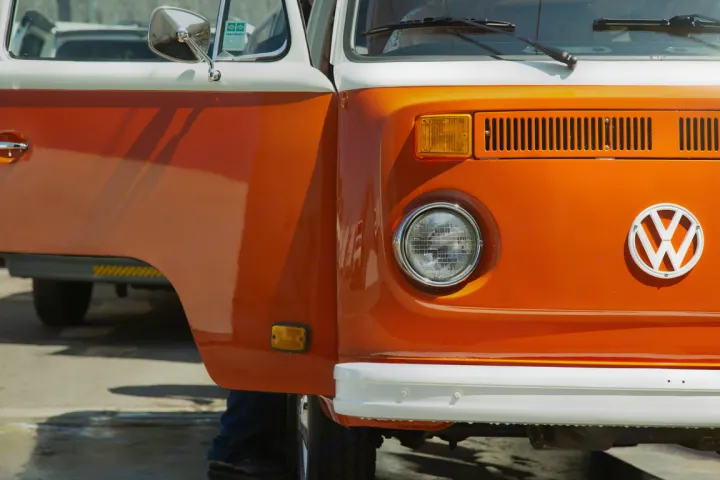 A vibrant orange and white classic VW bus, with its side door open, perfect for a memorable RV rental trip.. Volkswagen westfalia 1979