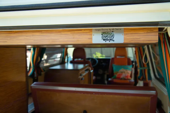 Inside a vintage camper van with wooden interior and 'Vintage Surf Wagons' plaque, ready for an RV rental adventure.. Volkswagen westfalia 1979