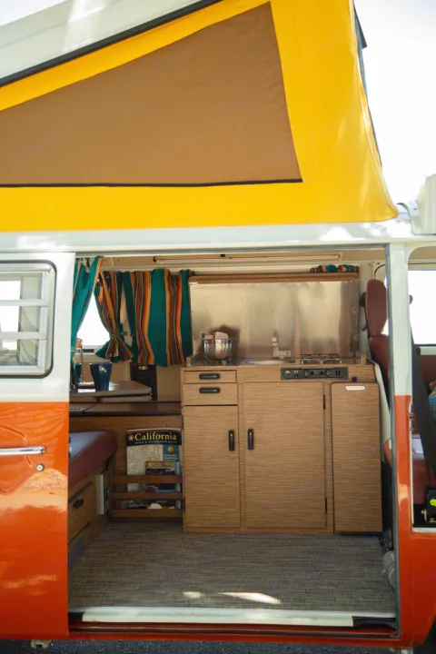 Step inside this charming vintage camper RV rental! Features a compact kitchen, cozy seating, and open pop-top for adventures.. Volkswagen westfalia 1979