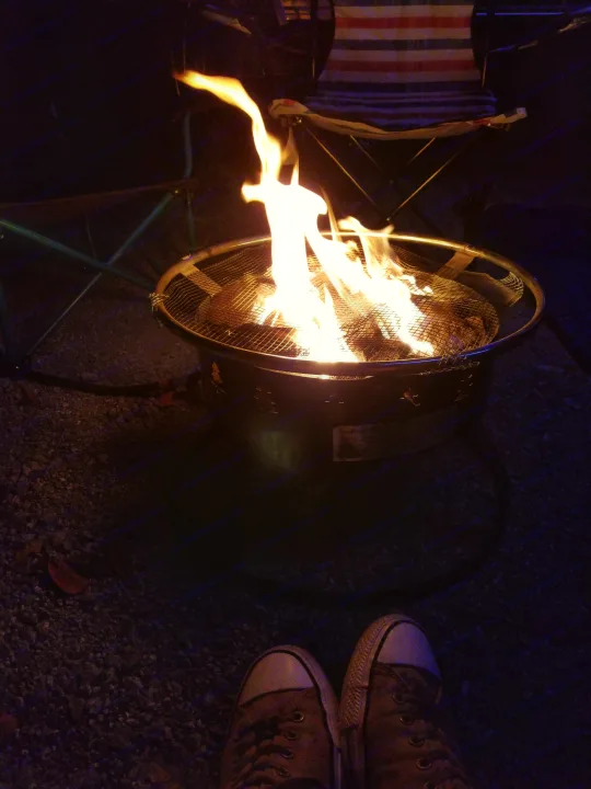 Evening at the RV rental: a warm fire pit illuminates feet in sneakers & camp chairs for a relaxing night.. Other Other 2019