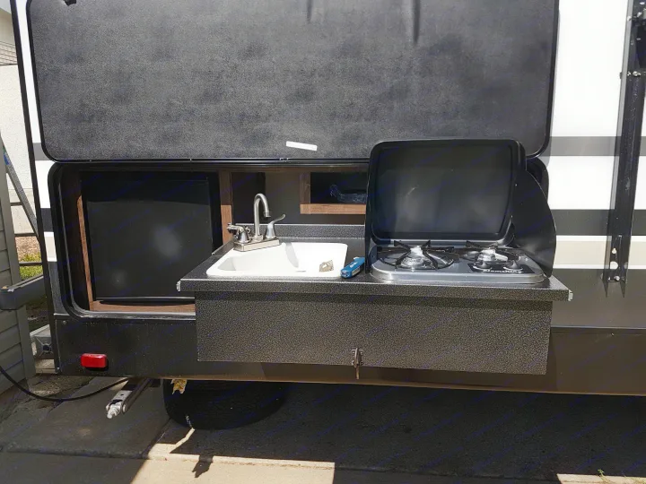 RV rental's outdoor kitchen featuring a FlameKing stove & sink, ready for campsite cooking.. Cruiser Rv Corp Radiance 2019
