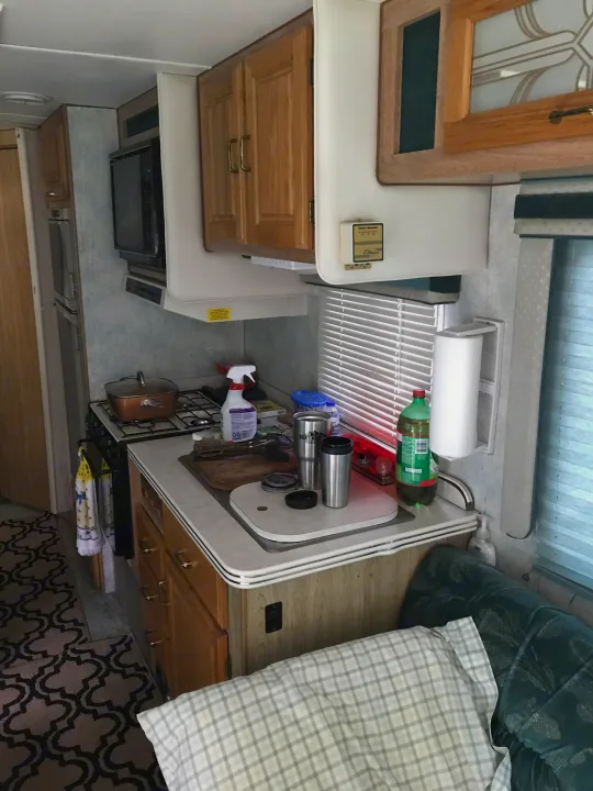 Compact RV rental interior featuring a functional kitchen with stove, microwave, counter, and a cozy living area with seating.. Gulf Stream Sun Stream 1995