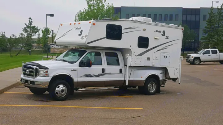 White Ford dually truck with a large Arctic Fox truck camper, ideal for an RV rental getaway.. Adventurer F350 2006