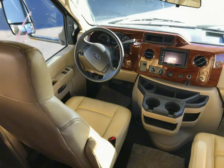 RV rental's clean driver cockpit: tan leather seats, Ford steering wheel, and detailed wood-grain dashboard.. Forester 3271 LE 2018