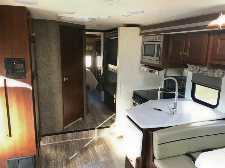 Spacious RV rental interior featuring a full kitchen, comfortable dinette, and visible bunk beds beyond.. Forester 3271 LE 2018