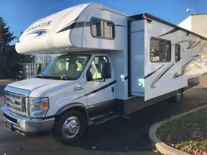 White Forester by Forest River Class C motorhome, perfect for rv rental, parked on a sunny day with its side extended.. Forester 3271 LE 2018