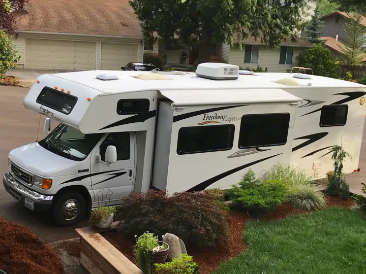 White Freedom Express rv rental motorhome with slide-out extended, parked in a driveway, ready for travel adventures.. Other Other 2008