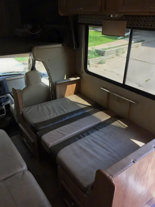 Spacious RV rental interior with a convertible dinette transformed into a cozy bed, offering comfortable seating and sleeping.. Gulf Stream Conquest 2018