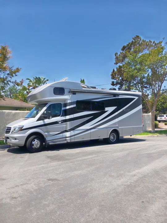 Silver & black Navion RV rental parked on a sunny street, ready for adventure.. Itasca Navion 2016