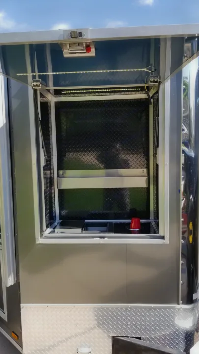 Open serving window of a dark gray RV rental, featuring diamond plate interior, LED lights, and shelves.. GameDay Mobile Marketer GameDay Mobile Marketer 2020