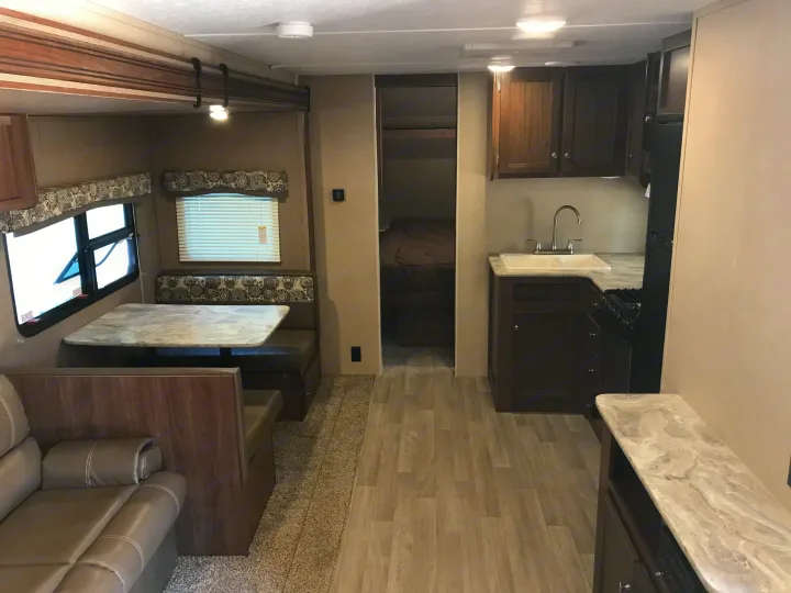 Inside a spacious **rv rental**, showing the kitchen, dining, and living areas with modern decor.. Dutchmen Coleman 2017