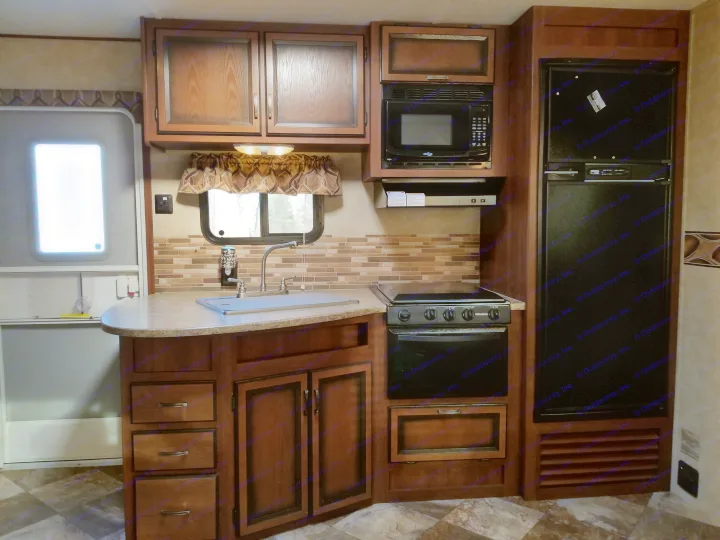Well-equipped RV rental kitchen featuring a sink, stove, microwave, fridge, and storage. Perfect for travel cooking.. Crossroads Zinger 2012