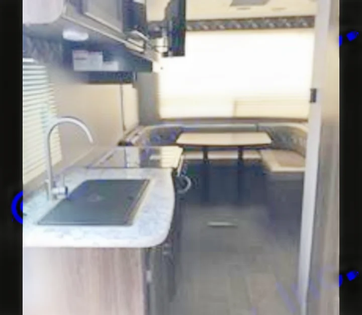 Spacious RV rental interior: modern kitchen with sink/stove on left, ample U-shaped dinette seating with table at rear window.. Keystone Bullet 2018