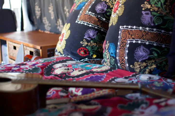 Colorful, cozy RV rental interior with embroidered pillows, patterned bedding, and a guitar for travels.. Mercedes-Benz Sprinter 2005