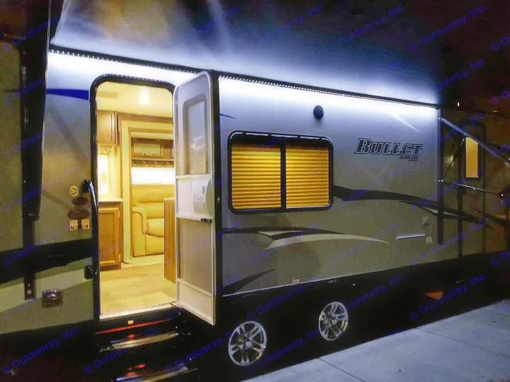 Modern RV rental at night with bright LED awning lights and inviting interior visible through the open door.. Keystone Bullet 2018