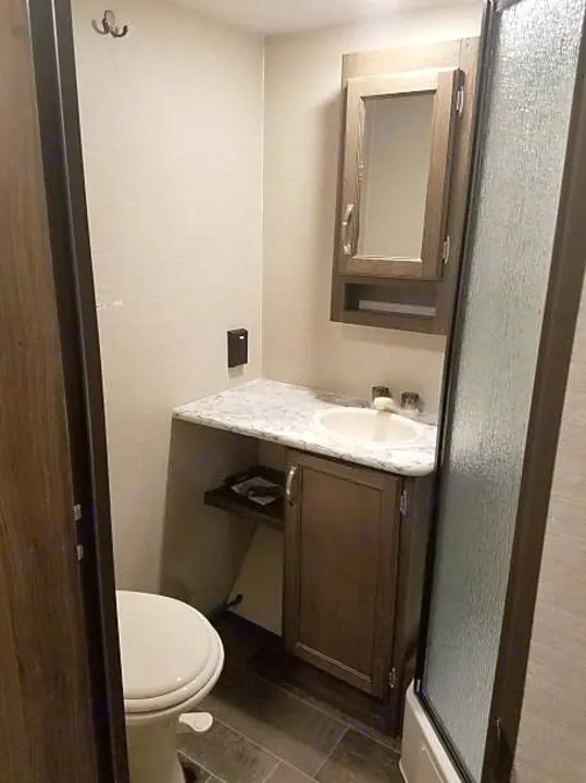 RV rental bathroom: features toilet, sink vanity, mirrored cabinet, and shower. Clean and modern.. Keystone Bullet 2018