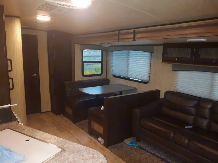 Inside an rv rental: a cozy living and dining area with a plush sofa, dinette booth, and kitchen counter.. Heartland Sundance 2018