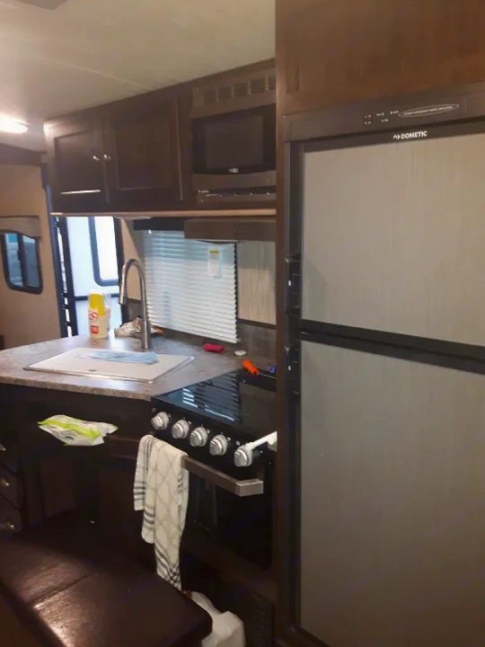 Explore this functional RV rental kitchen, featuring a sink, microwave, stove, oven, and Dometic fridge for your travels.. Heartland Sundance 2018