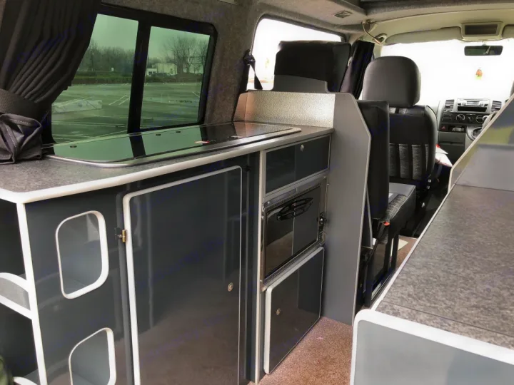 This RV rental campervan features a compact kitchen with stovetop, microwave, and custom storage cabinets, plus comfortable seating.. Volkswagen T5 Vivante 2015