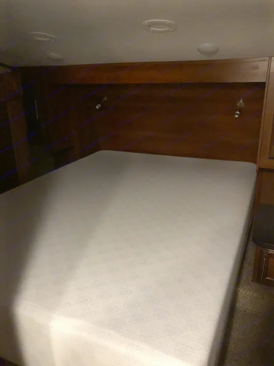A clean, white mattress on an unmade bed in a dimly lit RV bedroom. Features a wooden headboard, ceiling lights, perfect for your rv rental.. Jayco 27.5 BHS 2018