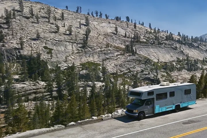 RV rental parked on a scenic mountain road, surrounded by majestic rocky peaks and evergreen trees under a clear sky.. Other Other 1992