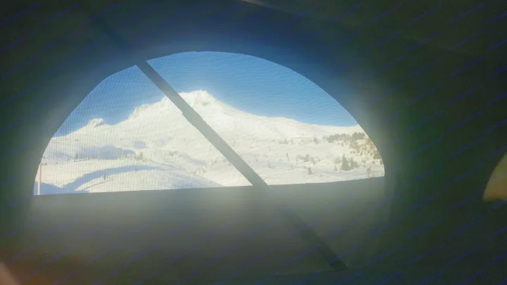 RV rental window offers a stunning view of a snow-covered mountain through its mesh screen. Perfect winter getaway scenery.. Volkswagen Westfalia 2002